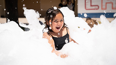 Summer Ed camp student playing in large amount of foam bubbles