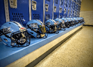 Row of football helmets on bench in locker room