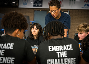 Students working together at table with tshirts reading Embrace the Challenge